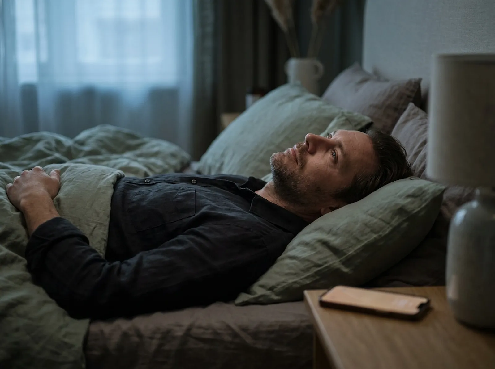 Mann liegt nachts wach im Bett und kann nicht abschalten &ndash; Symptom von chronischem Dauerstress